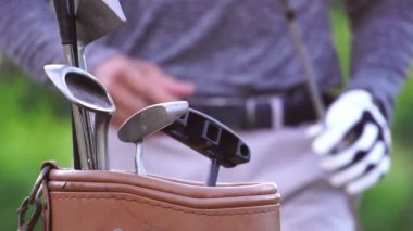 Golf çantasının içine sopa koyan adamın yakın plan görüntüsü.
