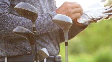 Golf çantasının yanında eldiven giyen adamın yakın plan görüntüsü.