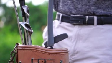 Golf çantasının içine sopa koyan adamın yakın plan görüntüsü.