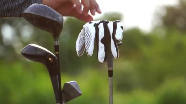 Golf çantasının yanında eldiven giyen adamın yakın plan görüntüsü.