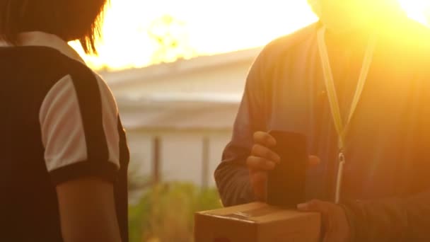 Teslimatçı Müşteriye Paket Teslim Ediyor Gün Batımında Akıllı Telefon Kuryesine — Stok video