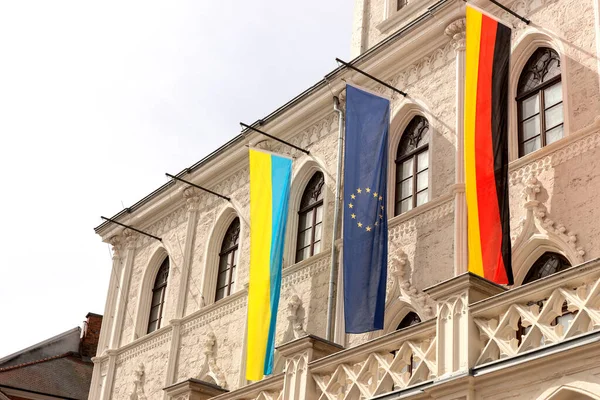 Tarihi bir binanın önünde Ukrayna, Almanya ve Avrupa Birliği bayrakları yan yana