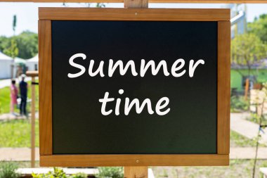 Üzerinde yazı olan siyah karatahta. Yazın bahçede.