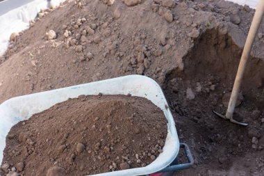 Bahçe işleri için hazırlık. Toprak yığınının önünde kürek ve el arabası