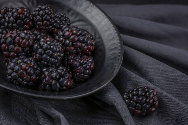 Blackberries in a black  bowl on a black background.