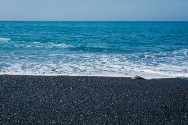 Volkanik siyah kumsal ve dalgaların resmi