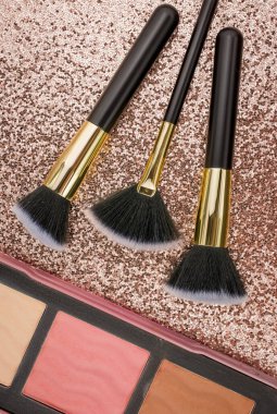 Altın arka planda farklı boyutlarda makyaj fırçaları