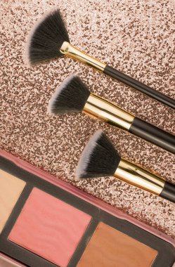 Altın arka planda farklı boyutlarda makyaj fırçaları
