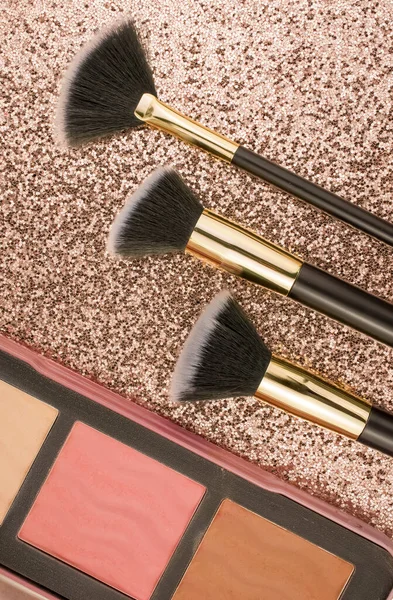 Altın arka planda farklı boyutlarda makyaj fırçaları