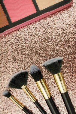 Altın arka planda farklı boyutlarda makyaj fırçaları