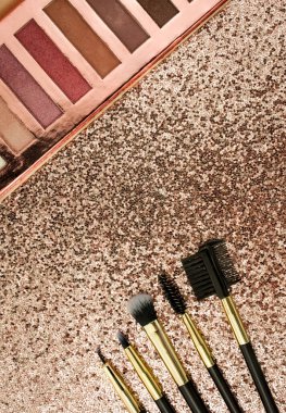 Altın arka planda farklı boyutlarda makyaj fırçaları