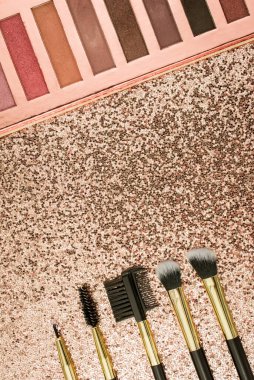 Altın arka planda farklı boyutlarda makyaj fırçaları