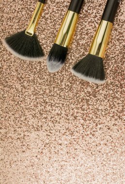 Altın arka planda farklı boyutlarda makyaj fırçaları