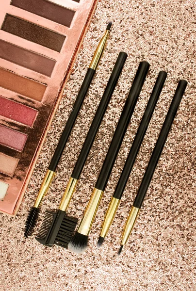 Altın arka planda farklı boyutlarda makyaj fırçaları