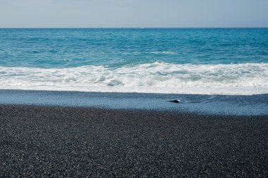 Volkanik siyah kumsal ve dalgaların resmi