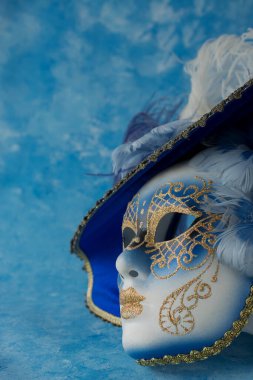 Mavi zemin üzerinde zarif Venedik maskesi resmi.