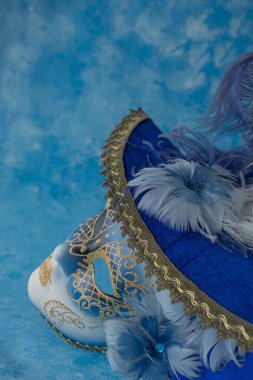 Mavi zemin üzerinde zarif Venedik maskesi resmi.