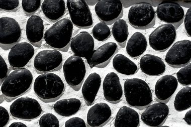 Wall closeup hand construction river round black stones closeup 