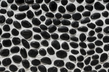 Wall closeup hand construction river round black stones closeup 