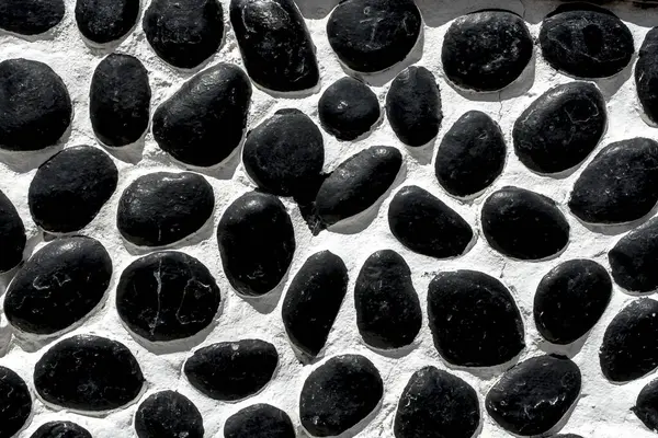 Wall closeup hand construction river round black stones closeup 