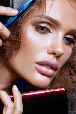 Beautiful woman handling phon. Bright makeup and beautiful hairstyle.