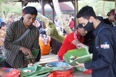 İnsanlar Cava Şükran Günü 'nde birlikte yemek yiyorlar. Sanggar sahilinde, Tulung Agung 'da, Doğu Java' da, Endonezya 'da, Sedekah Bumi' de yemek yiyen insanlar var.