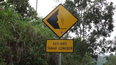 Doğal bir geçmişi olan sarı bir tabela. Hati-hati tanah longsor heyelanlara dikkat et demek.
