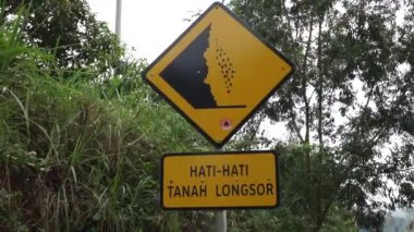 Doğal bir geçmişi olan sarı bir tabela. Hati-hati tanah longsor heyelanlara dikkat et demek.