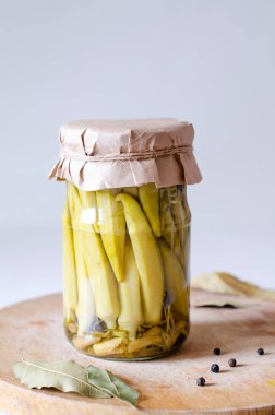 Gri arka planda cam bir kavanozda ev yapımı bamya turşusu. Sebzelerin korunması. Yakın plan..