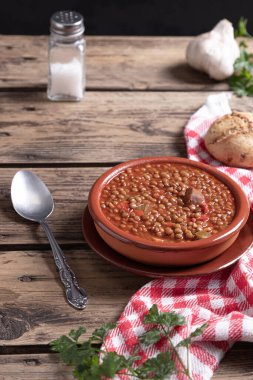 Ahşap arka planda malzemelerle ev yapımı mercimek çorbası. Dikey format. Geleneksel İspanyolca yemek kavramı.