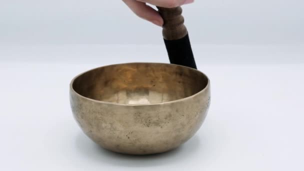 Tibetan singing bowl for meditation. A womans hand plays with a wand on a singing bowl. — Stock Video