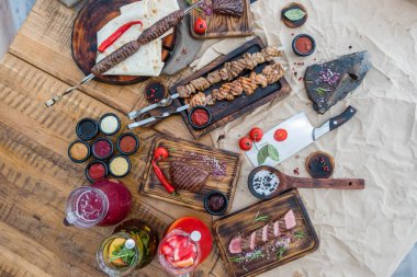 Düz kompozisyon, kızarmış et, şiş kebap, biftek, lula kebap, sebze ve baharatlar ahşap bir masada.