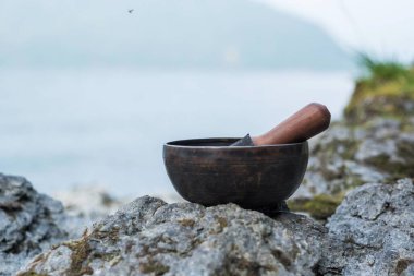 Tibet şarkı kasesinde Sanskritçe bir resim göl kıyısına işlenmiş..