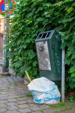 Brüksel, Belçika - Haziran 12019: Yeşil bir çöp tenekesinin yanında beyaz Brüksel çöp torbası.