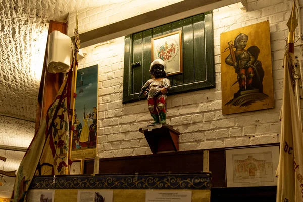 Manneken Piss statue disguised as crossbow man in cellar against white wall