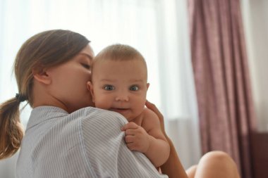 Annelerin kucağında neşeli bir bebek. Aile anları