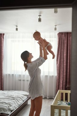 Gülümseyen anne, sevimli oğlunu pencereden fırlatıyor.