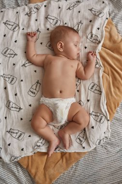 Beyaz battaniyede bebek bezi içinde, düz yatıyordu.