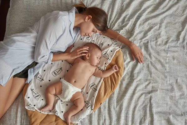 Caring mother guarding her adorable sleeping baby