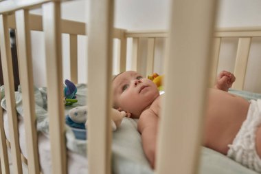 Beşikte güzel bir bebek, ahşap parmaklıkların ardında bir portre