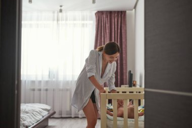 Beşikteki çocuğa gülümseyen güzel anne.