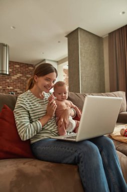 Gülümseyen anne ve çocuk dizüstü bilgisayarla konuşuyor.