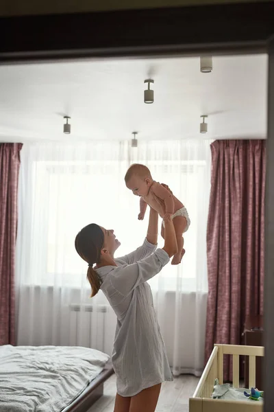 Lovely mummy holding baby high, lifestyle portrait — Stock Photo, Image