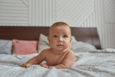 Anne-babanın yatağında çıplak masum bir bebek yatıyor.