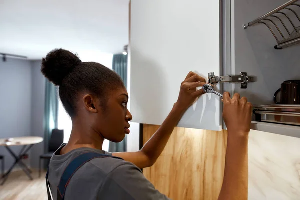 Młody wykwalifikowany mieszane rasy kobieta instalowanie drzwi szafy — Zdjęcie stockowe