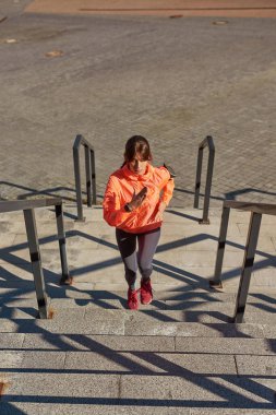 Spor giyim treninde aktif kız koşucu açık havada koşuyor.