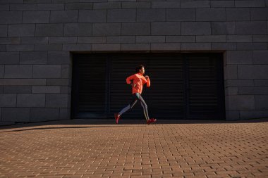 Etkin tonlu milenyum sporcusu kadın açık havada koşuyor.