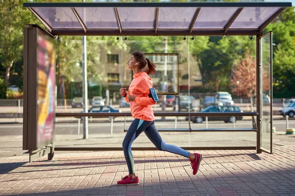 让千禧年女孩穿上运动服，用手机跑步 — 图库照片