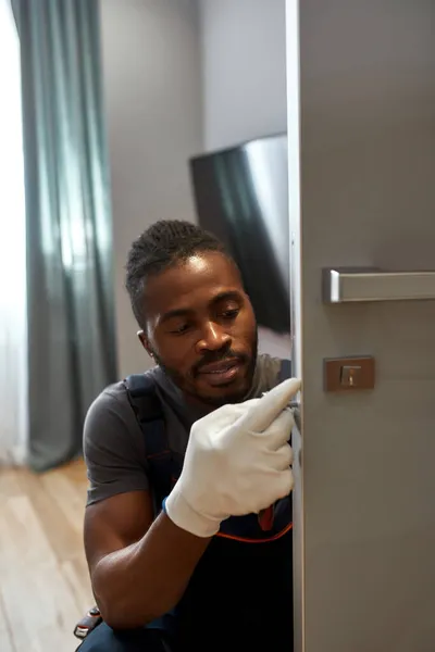 Joven trabajador arreglando cerradura de puerta de sala —  Fotos de Stock