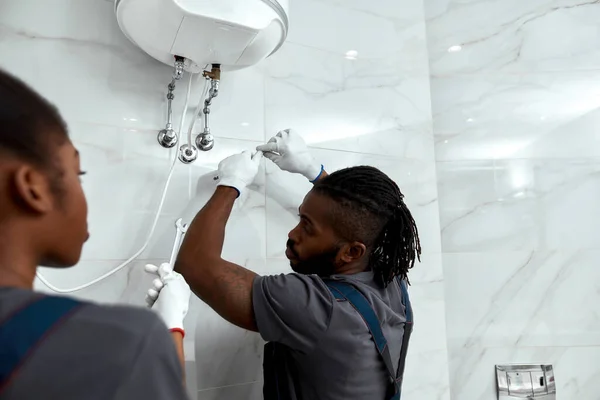 Joven mecánico inspeccionando la caldera eléctrica en casa —  Fotos de Stock